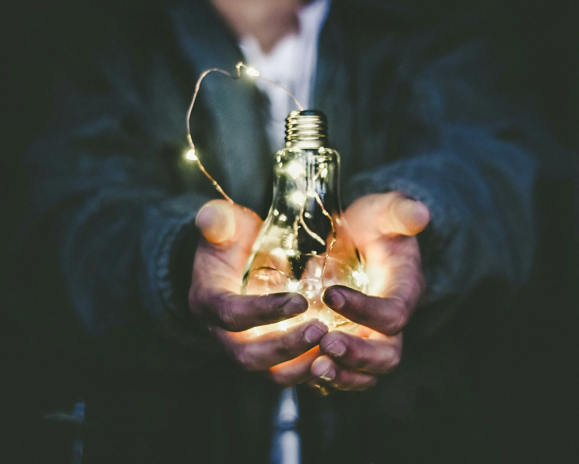Hand holding a lit bulb